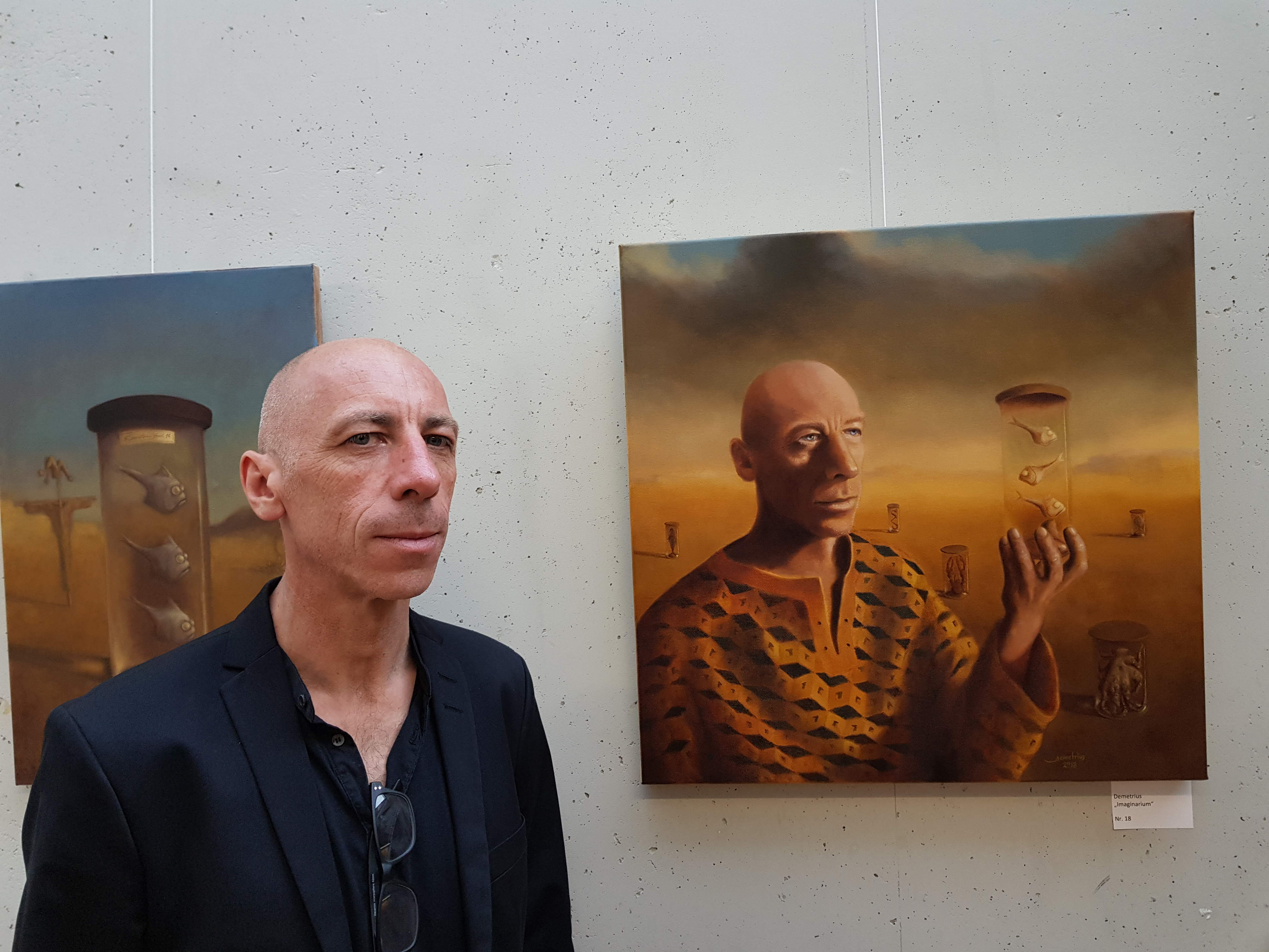 Künstler Laurent Bompard neben seinem Portrait in der Rathausgalerie in Eisenstadt